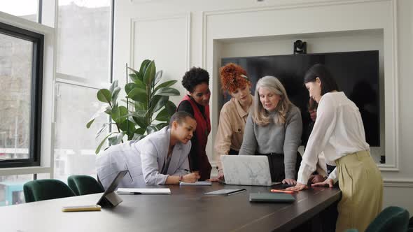 Slow motion of multi ethnic mixed age range women in creative business meeting with laptop alt