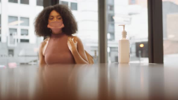 Female Office Worker Uses Hand Sanitiser In Reception As She Arrives For Work During Health Pandemic alt