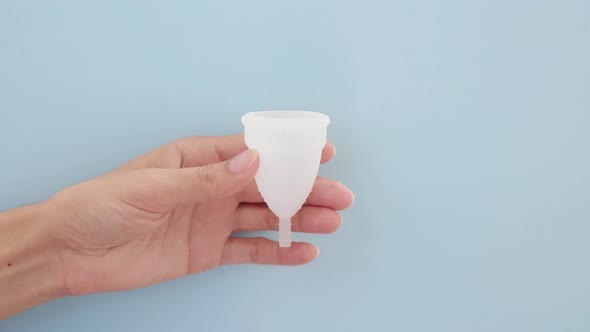 A Woman Holds a Menstrual Cup in Her Hands