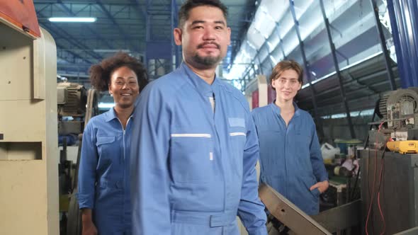 Multiracial workers collaborate and express happy work in an industrial factory.