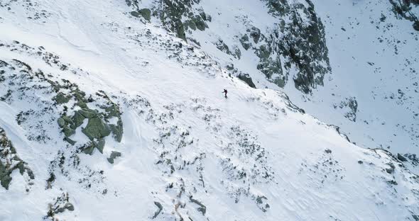 Side Aerial Over Winter Snowy Mountain with Mountaineering Skier People Walking Up Climbing