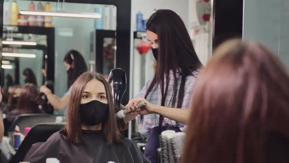 Woman in Protective Mask Works with Client Hair in Salon