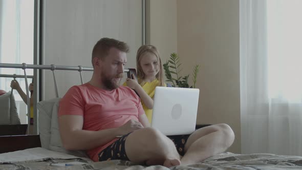 Man with Laptop at Home on Bed