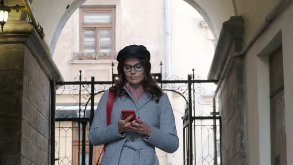 Young Beautiful Girl In Autumn Dress Uses A Smartphone.