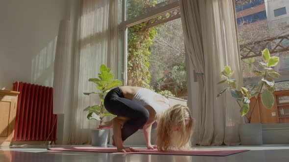 Long Hair Beautiful Slim Caucasian Woman in a Sports Bra and Leggins Doing Yoga Poses and Handstand