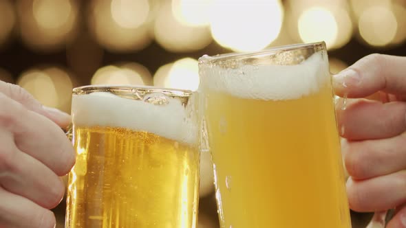 Close-up shot of two hands toast beer spilling beer bokeh background.