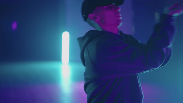 Stylish Male Dancer Moves to Music in a Smoky Room with Neon Lighting alt