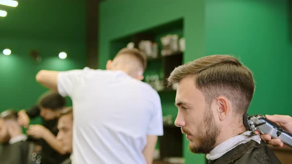 Hand Holds Clipper and Trims Customer Hair in Barbershop alt
