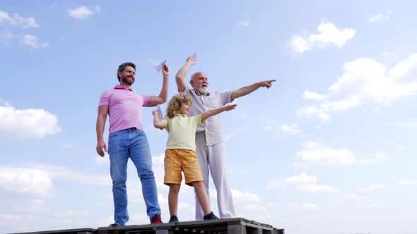 Family of Boy Child with Father and Old Man Point Fingers Holding Paper Planes Skyhigh Throwing alt