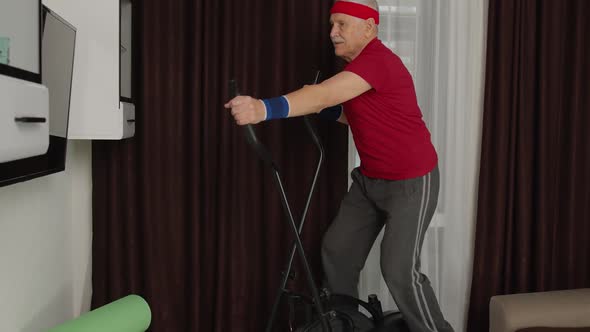 Active Healthy Senior Old Mature Man in Sportswear Using Orbitrek Training Cardio Workout at Home alt
