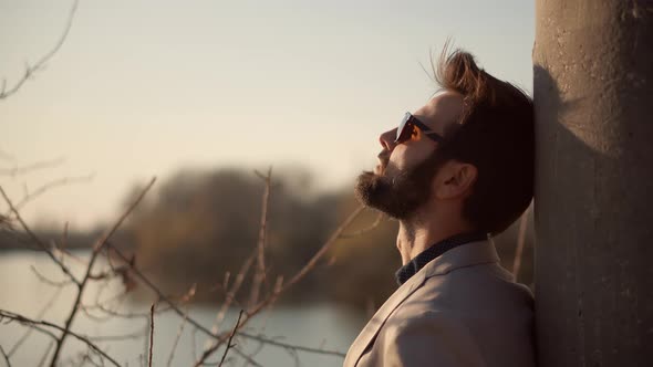 Businessman Relaxing On River And Thinking About Future. Man Resting On Nature Breathing Fresh Air. alt