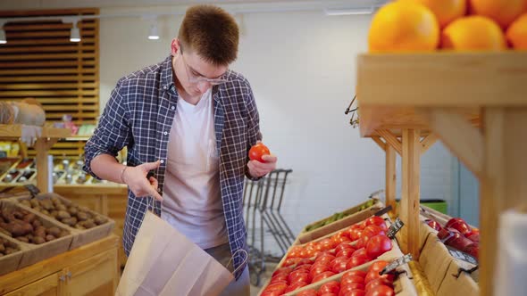 Vegetarian is Shopping in Grocery Choosing Organic Tomato in Vegetable Aisle alt