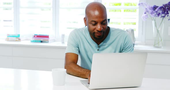 Man using laptop in kitchen 4k alt