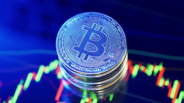 Golden Bitcoin Coins are Rotating on a Candles Chart Background alt