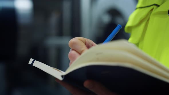 Woman Hands Writing Data in Notebook on Big Logistic Company Closeup alt