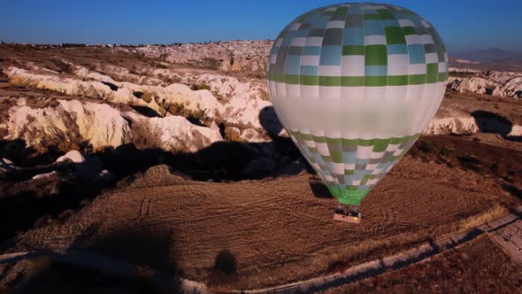 Aerial View of Hot Air Balloon with Tourists in Basket Landing on the Ground at Cappadocia Valley alt