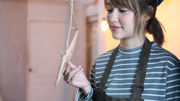 Business owner attractive young Asian woman in apron hanging we're open alt