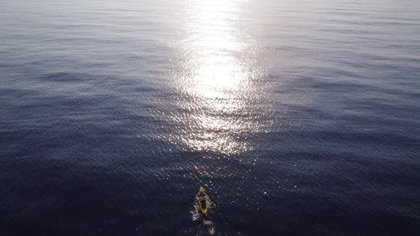 Fisherman trolling in kayak at mediterranean sea aerial drone view in middle of ocean. alt