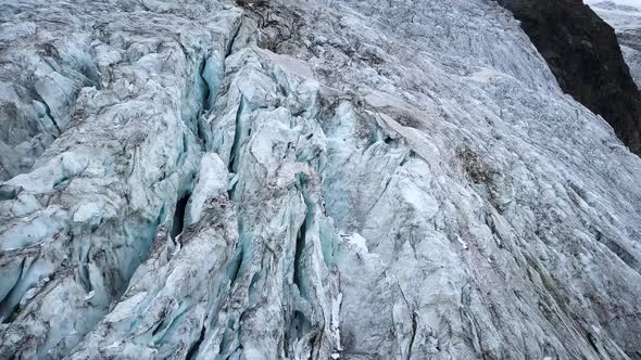 Aerial view of a mountain glacier with a lot of craks melting in the Swiss alps alt
