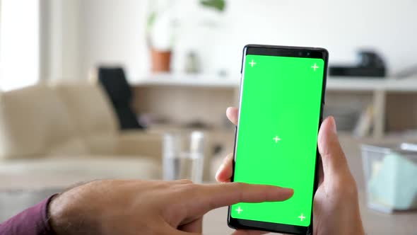 Close Up of Man Using a Modern Smartphone with Green Screen Chroma Mock Up on It alt