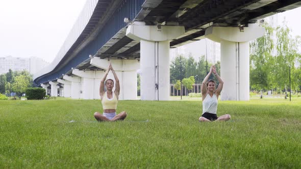 Women Do Yoga Exercises in Lotus Poses on Lush Green Grass