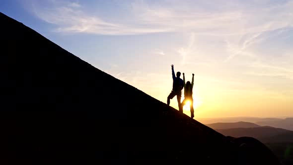 A Young Couple Happily Raises Their Hands on the Mountain