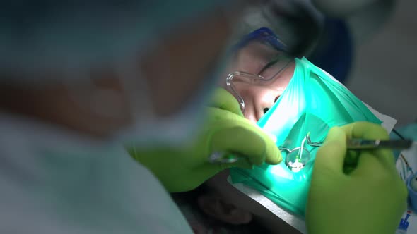 Closeup Dentist with Dental Mirror and Tweezers Placing Protaper in Ill Tooth in Slow Motion alt