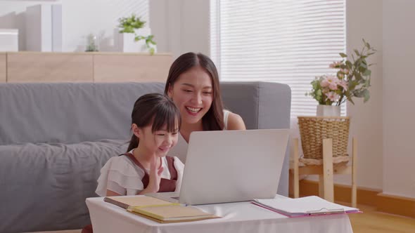 Asian young mother and her daughter have video call conference with family having fun together alt