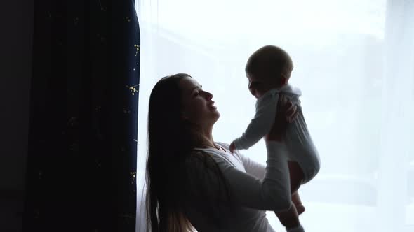 Silhouette Loving Tender Caucasian Young Mum Holding Adorable Cute Baby Boy Son Embracing Kissing