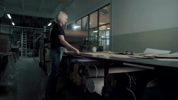 Fashion designer technologist at a clothing factory prepares a piece of fabric