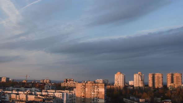 Grey Spindrift Clouds in Blue Sky Over Cityscape in Sunset Light