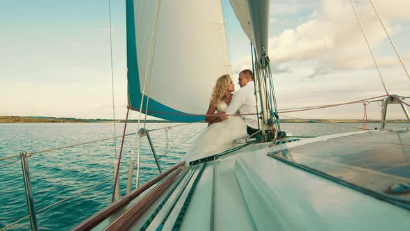 The Newlyweds Are Sailing on the Lake Aboard the Yacht. They Enjoy Each Other, Look and Smile alt