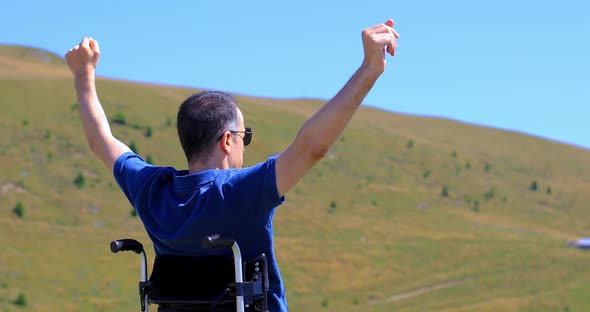 Optimistic Handicapped Man Sitting on Wheelchair on Mountain