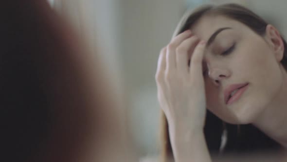 Woman grooming hair in mirror