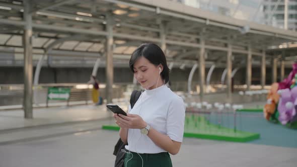 Portrait of asian woman with earphone listening music and using smartphone