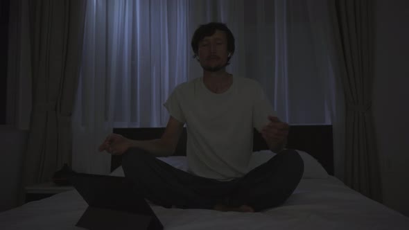 A Man at Night Turns on a Meditation Relaxation Application on His Tablet to Relax Before Going to alt