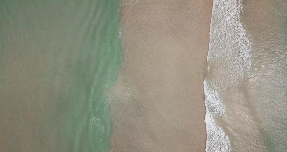 Vertical view of sand and beach with blue clean sea water. Tropical aerial landscape with waves alt