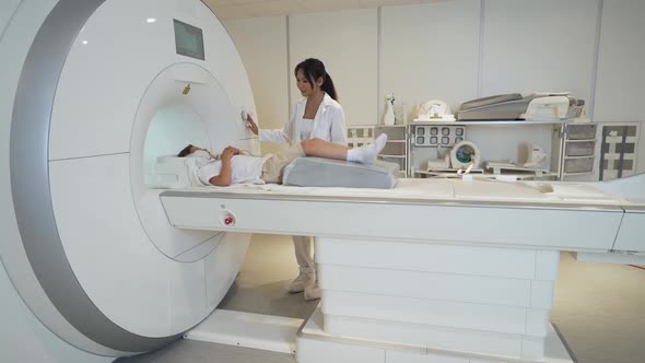 Magnetic Resonance Imaging Young Asian Woman Doctor Performs a Magnetic Tomographic Examination of a alt