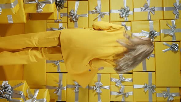 A Happy Blonde in a Yellow Suit and a Yellow Purse in Her Hands Poses in Front of the Camera Against alt