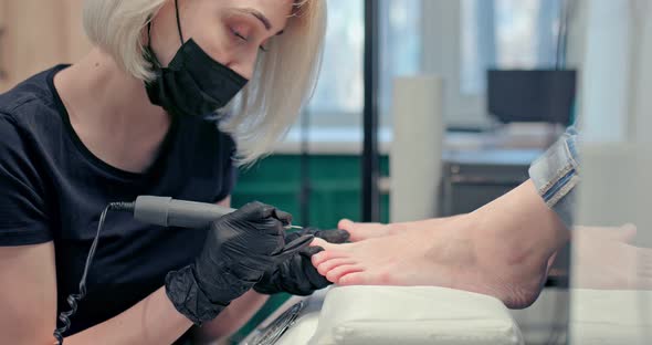 Master Does a Professional Pedicure Using a Milling Machine Processing Cuticles alt