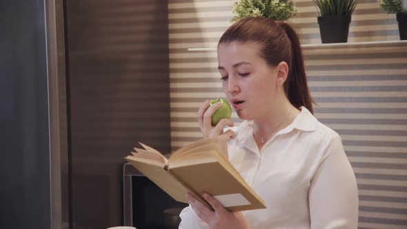 Young Adult Woman Reading Book in Kitchen Room