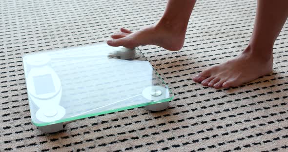 Female measuring weight on health scale alt