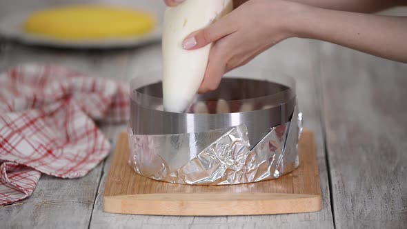 Squeeze the cream from pastry bag. Cooking homemade cake inside cake ring.