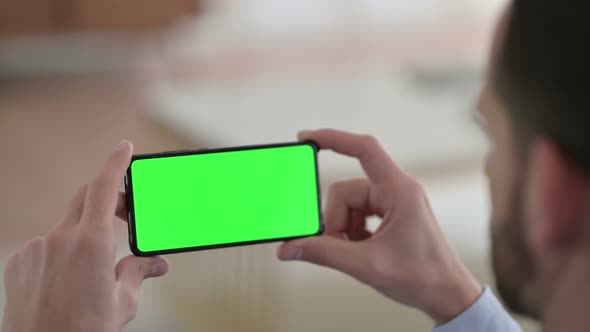 Young Man Watching Smartphone with Green Chroma Screen  alt