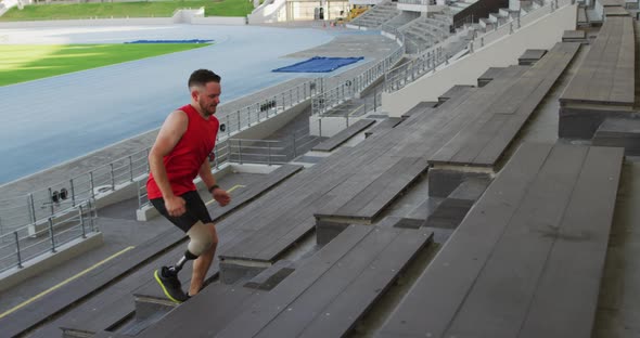 Caucasian disabled male athlete with prosthetic leg training, running up stairs alt