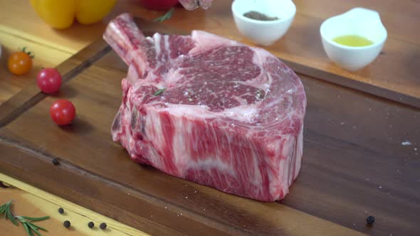 Chef cook season fresh chunk of deli piece of beef with sea salt and grounded spicy peppers.