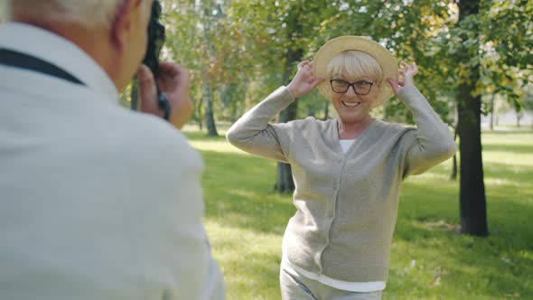 Slow Motion of Mature Woman Posing for Photo Camera Having Fun with Husband in Summer Park alt
