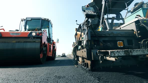 Fresh Asphalt Road with Paving Machines in a Front View. Road Construction Process alt