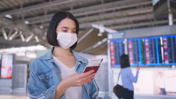 Asian woman passenger wearing face mask, walking in airport terminal to boarding gate to airplane. alt