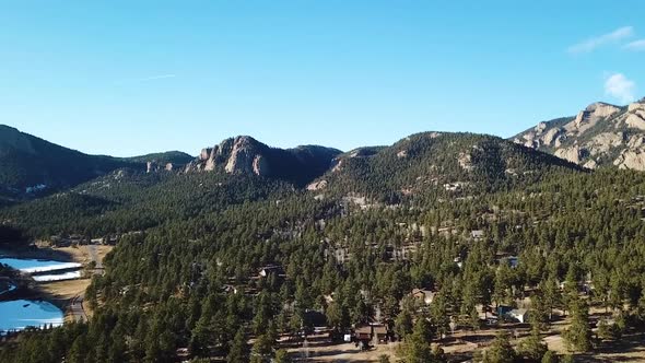 Flying over Colorado mountain trees and frozen lake alt